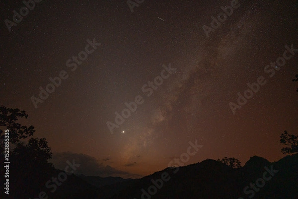 Obraz Milky Way above mountains at night in autumn. Landscape with mountain valley, low clouds, purple starry sky with milky way. The Milky Way shines on a cold night in the north of Thailand