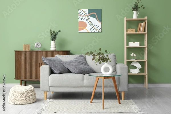 Fototapeta Sofa, pouf, table and vase with eucalyptus branches in interior of living room
