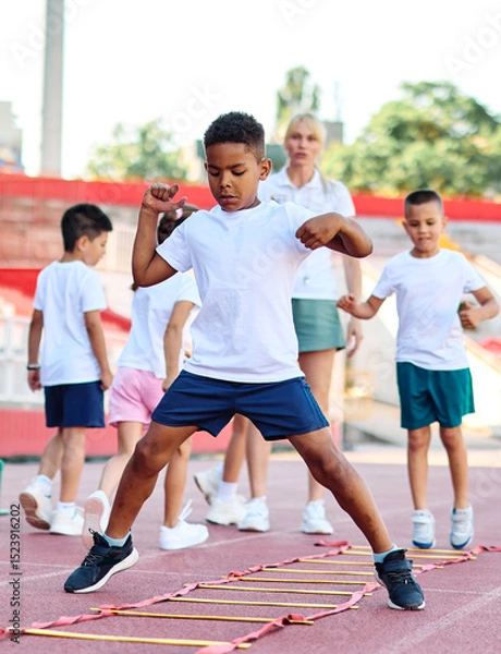 Fototapeta Young children having athletic exercise class running on the track, healthy lifestyle and children sport education concepts