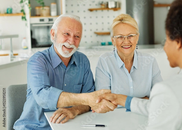 Fototapeta Portrait of a businessman or real estate agent or doctor shaking hands and signing a deal contract with senior couple in his office