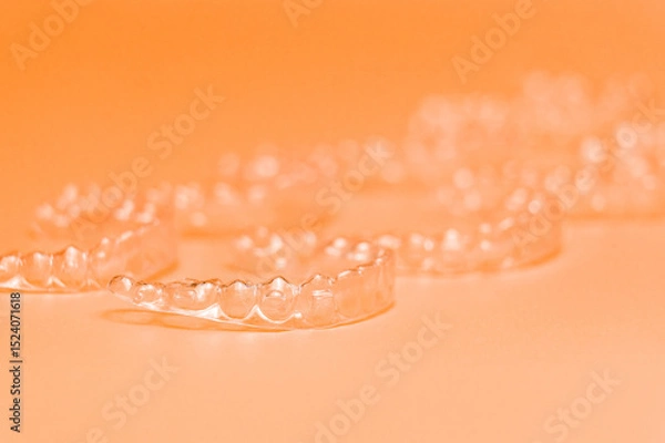 Obraz Orthodontic silicone aligner background. Advertisement of invisible braces retainer. Medical website concept. Pros and cons of aligners. peach saturated background