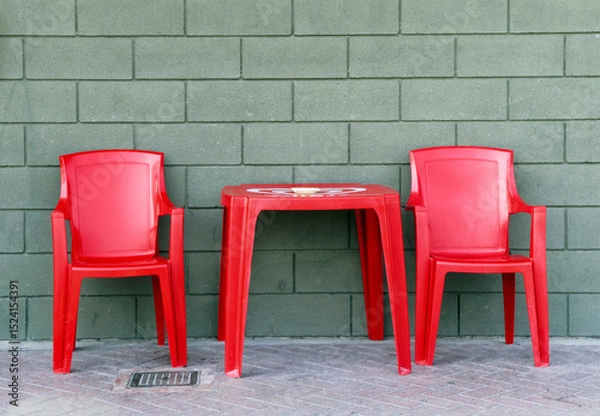 Fototapeta red plastic chairs and table outside a bar