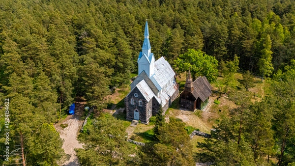 Fototapeta Historic church amidst lush forest on Ruhnu Island, Estonia, showcasing unique architecture