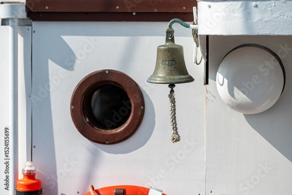 Fototapeta Bell and porthole on a boat during daylight, capturing marine ambiance and design elements