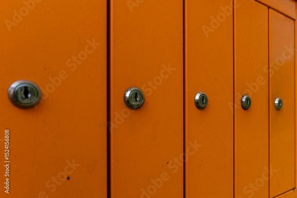 Fototapeta Bright orange mailboxes lined up in an urban setting during daylight hours