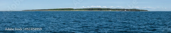 Fototapeta View of a peaceful coastline with lush greenery and calm blue waters on a sunny day