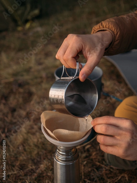 Obraz Close view of outdoor coffee brewing with metal cup pouring into paper filter funnel