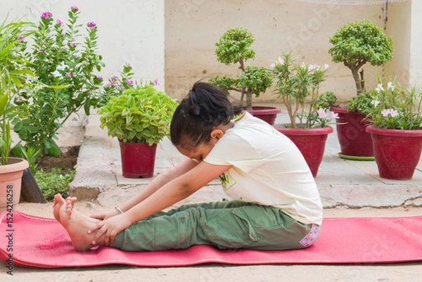 Obraz Indian Girl Child Practicing Paschimottanasana, also known as the Seated Forward Bend Pose Yoga  outdoors in the fresh air. promotes spine flexibility, digestion, and inner peace. 