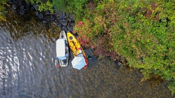 Fototapeta Two kayaks near small island in the middle of the lake view in aerial shot. Beautiful island in Canada. Aquatic sports in a kayak at the lake during summer