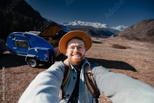 Obraz Young happy man hipster traveler making selfie background camper car on mountain. Concept one life adventure trip, vacation.
