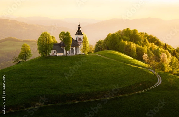 Obraz Sunset over a serene hilltop church in Slovenia with lush greenery