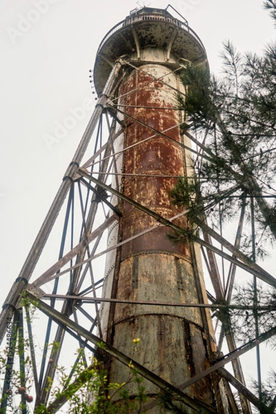 Obraz Old rusty lighthouse against the grey sky