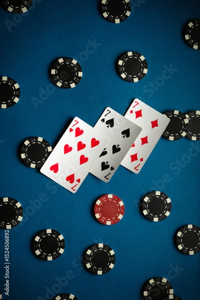 Fototapeta On the card table are three sevens and the playing chips from winning poker, displaying two pairs of cards and a lively atmosphere perfect for an evening of gaming