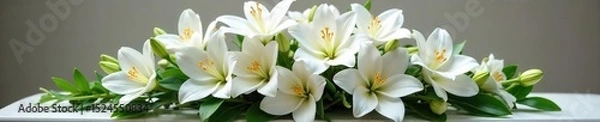 Fototapeta A serene arrangement of white lilies, roses, and orchids rests in a simple, elegant casket spray Perfect for sympathy, remembrance, and funeral service imagery , elegant, flowers, solemn