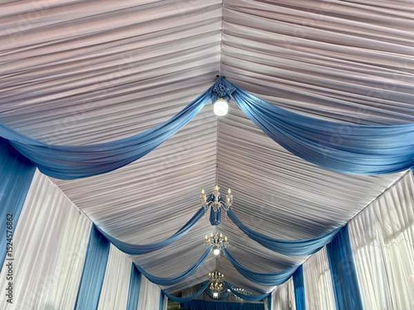 Fototapeta Party tent ceiling with wavy white and blue fabric decorated with small round lights