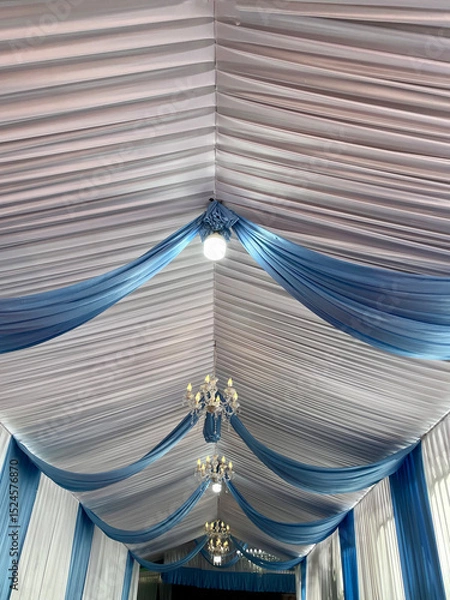 Fototapeta Party tent ceiling with wavy white and blue fabric decorated with small round lights