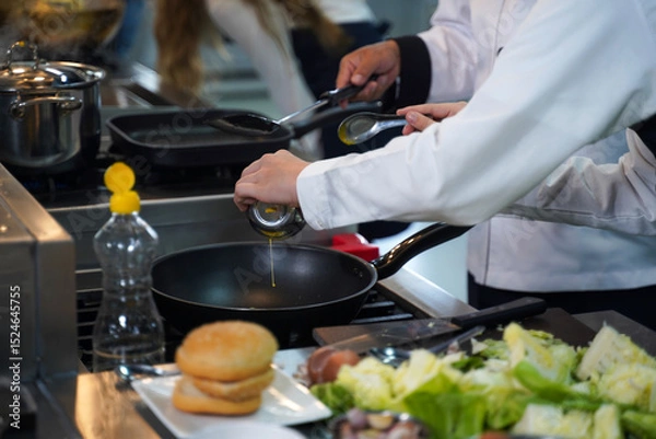 Fototapeta Close up.  Chef teacher teaches cooking to the group children in class kitchen room.  Chef preparing student for learning marking and cooking food at workshop.  Education Concept