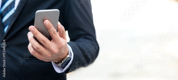 Fototapeta Close up hand businessman using smart phone to work with financial data in city. Business Concept