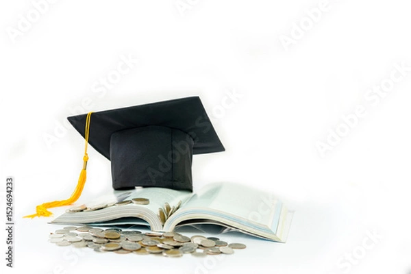 Fototapeta A graduation cap rests on an open book, with a pile of coins in front of it.