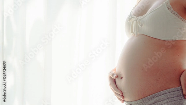 Obraz 4K Young happy pregnant woman posing in studio with white curtains in background