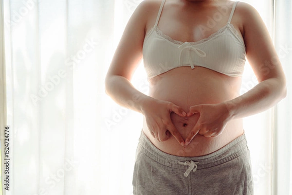 Obraz 4K Young happy pregnant woman posing in studio with white curtains in background
