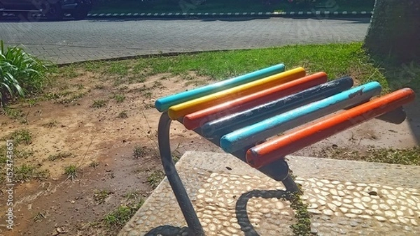 Fototapeta Vibrant park bench with multicolored wooden slats, ideal for outdoor seating and public space illustrations.