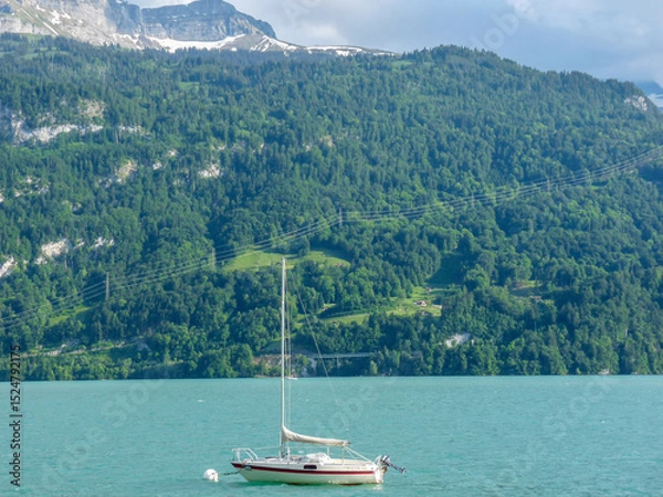 Obraz Switzerland, Meiringen, a small boat in a body of water with a mountain in the background