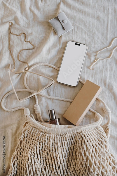 Fototapeta Smartphone and Accessories in Natural Mesh Bag on Neutral Fabric Background