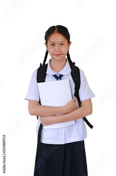 Obraz Portrait smiling Asian student girl in school uniform carrying backpack bag and cuddle a book while standing isolated on white studio background. Schoolgirl back to school concept.