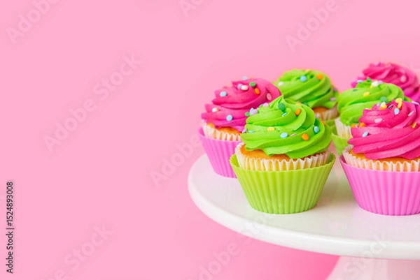Fototapeta Colorful cupcakes with swirled frosting and sprinkles on pink background