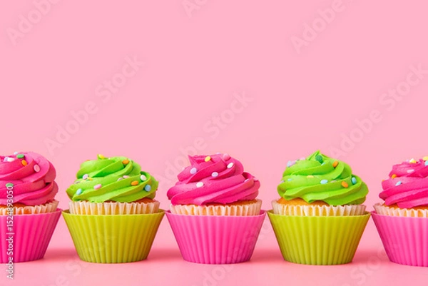 Fototapeta Colorful cupcakes with frosting and sprinkles in row on pink background