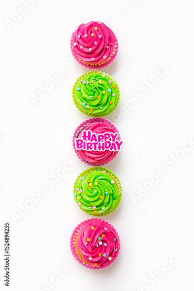 Fototapeta Top view of colorful iced cupcakes arranged in row on white background with birthday topper
