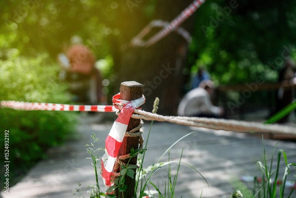 Fototapeta People ignoring safety rules by crossing the red-white barrier tape, demonstrating violation of established regulations