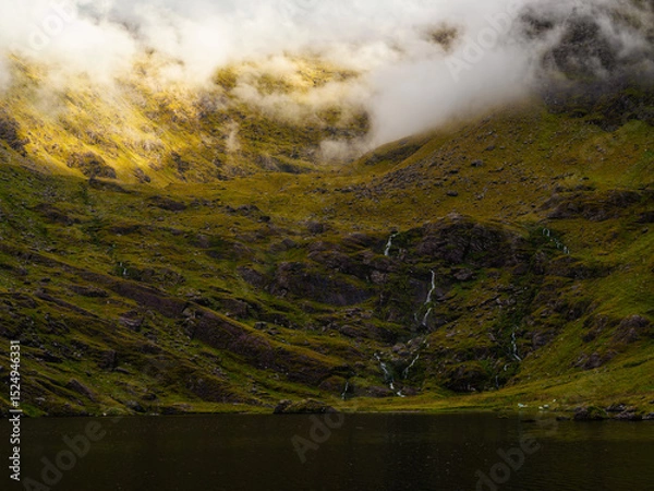 Fototapeta Green hillside meets Lough Callee and the sky, shrouded in cloud cover, giving it an atmospheric, mystical feel in Ireland.