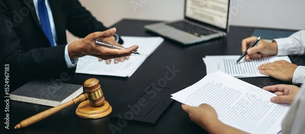 Obraz Three people are sitting at a table with legal documents and a gavel
