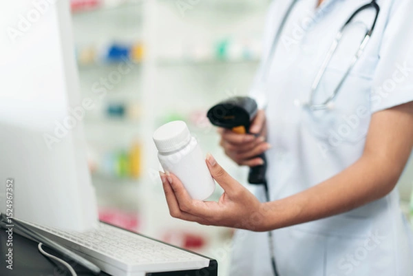 Obraz A woman in a white lab coat is holding a bottle of medicine