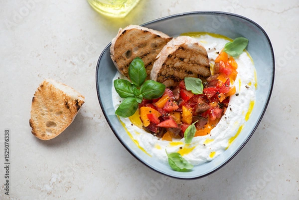 Fototapeta Ricotta dipping sauce with chopped tomatoes on a light-beige stone background, horizontal shot, high angle view