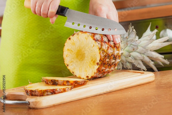 Obraz Woman chopping fresh pineapple on cutting board...