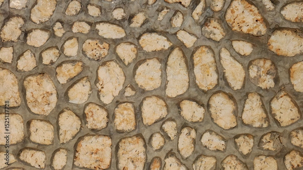 Fototapeta A rustic stone wall featuring irregularly shaped, light-colored rocks meticulously fitted together with dark mortar, forming a durable and textured surface.