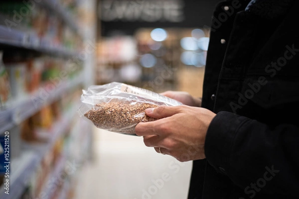 Obraz Close-up of a man's hands holding a cereal box while shopping at a supermarket. A realistic scene depicting grocery shopping, product selection, and daily consumer behavior.