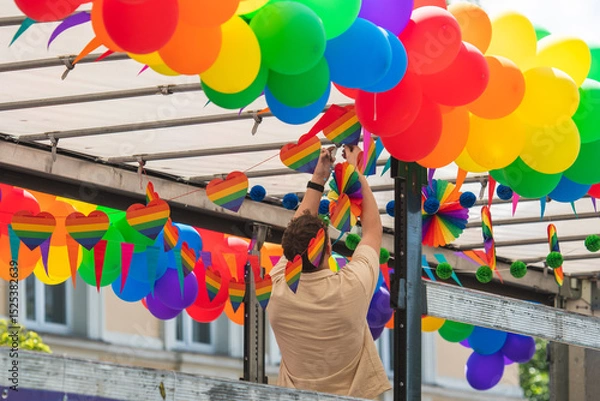 Fototapeta  Setting up rainbow coloured balloons, paper hearts and little flags on a truck during a LGBT+ pride parade