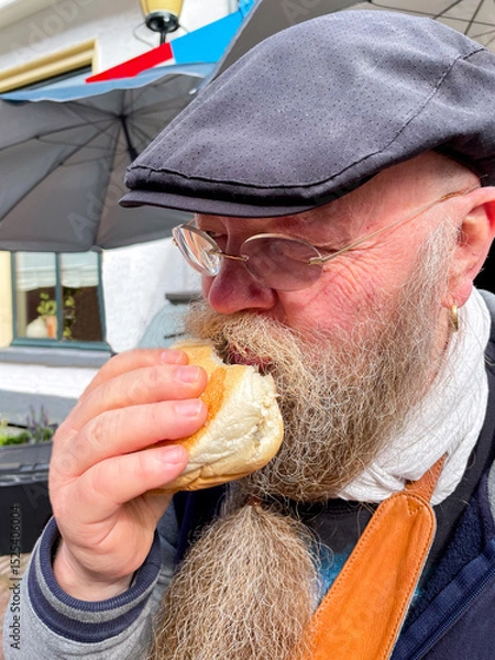 Obraz bärtiger Mann genießt ein Fischbrötchen mit Hering