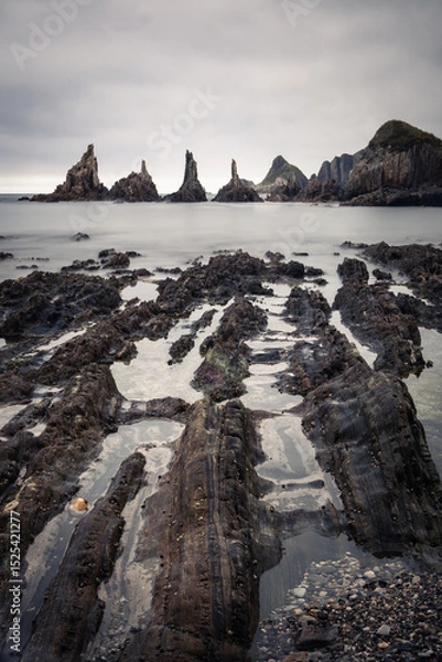 Obraz scenic seascape with rising rocks on the beach in long exposure