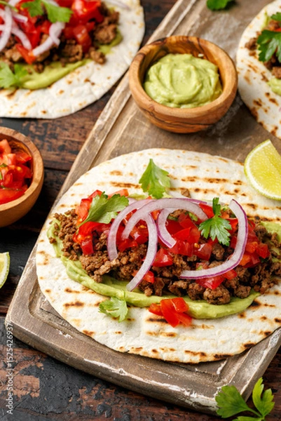 Fototapeta Tasty Beef Tacos with guacamole, tomato, onion and sauce. Tortilla Fast Food.