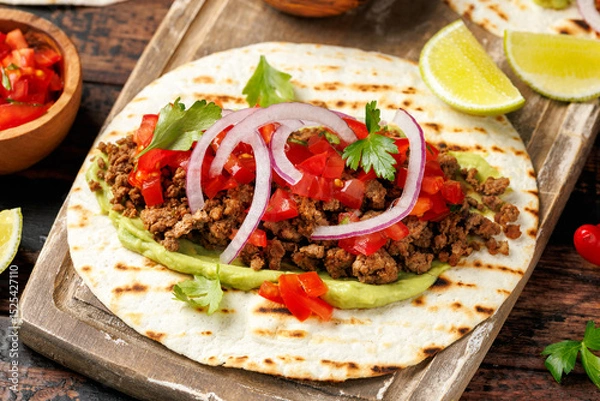 Fototapeta Tasty Beef Tacos with guacamole, tomato, onion and sauce. Tortilla Fast Food.