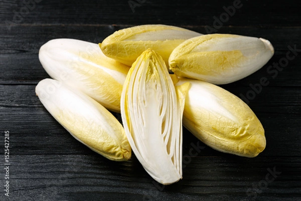 Fototapeta Raw chicory or endives salad roots on wooden background