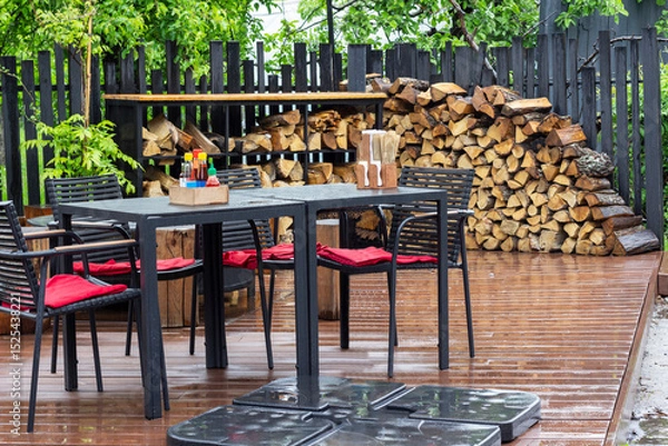 Fototapeta Table and chairs on the summer terrace of a cafe after the rain. Spices on the table.
