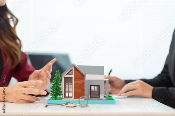 Obraz Inside a real estate office a real estate agent is using a house mockup to present the design and promotions that the client will receive when they sign sales contract. Real estate investment concept