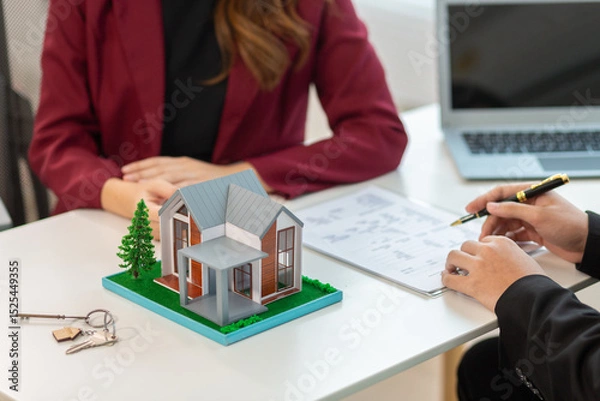 Obraz Real estate agent is in the office with the customer to prepare the documents for the real estate sale. The customer signs the sales contract before handing over the property to the customer.