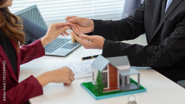 Obraz Real estate agent is talking to a customer inside office to hand over the house keys to the customer after the real estate sale contract is completed. Real estate investment concept